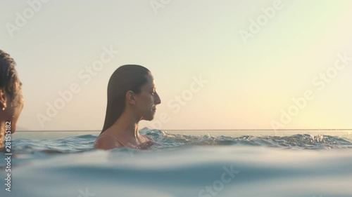 group of friends in swimming pool splashing playfully enjoying summer vacation having fun celebrating summertime at sunset 4k