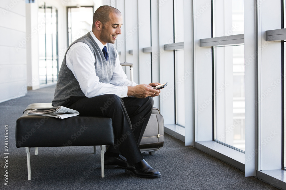 Smiling businessman using smartphone in office lobby Smiling businessman using smartphone in office lobby