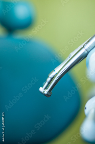 Close up of the metallic dentist tools with blue dentist chair on the background