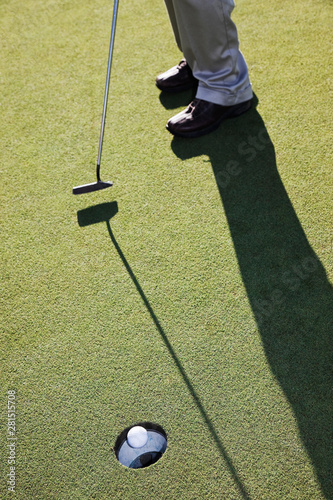 Low section of golfer hitting golf ball