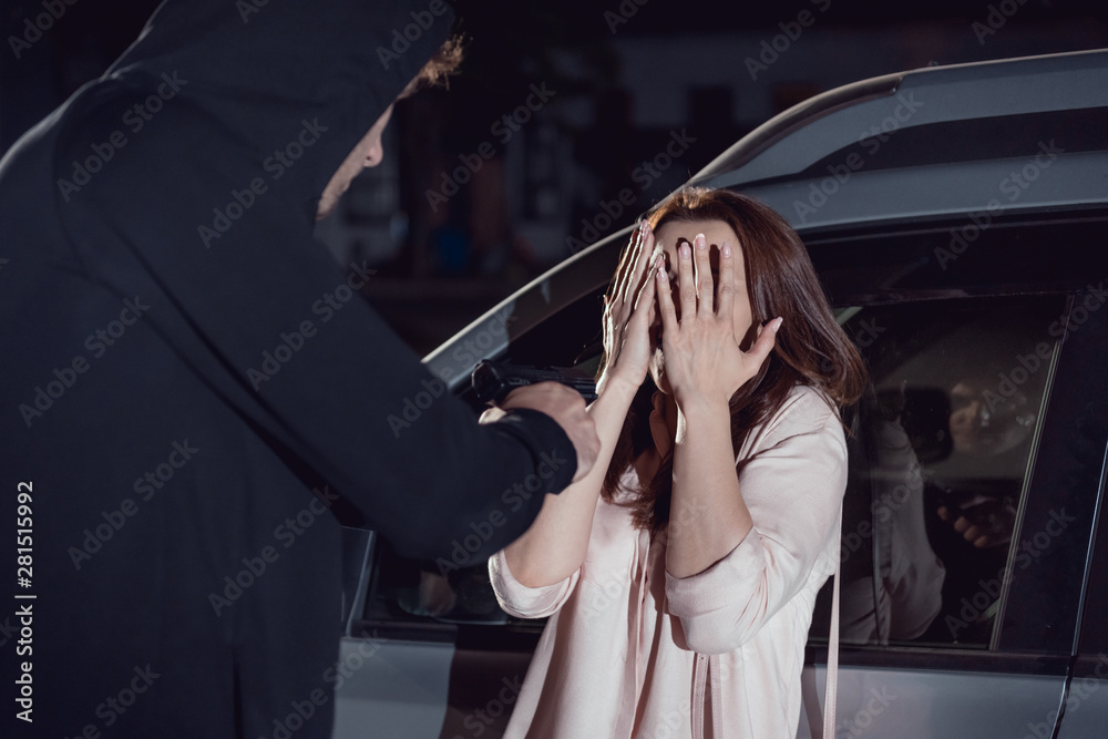 thief attacking woman covering face near car at night