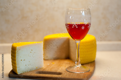 Minimalistic shot of a yellow notched cheese head and a glass of red wine on a bamboo stand