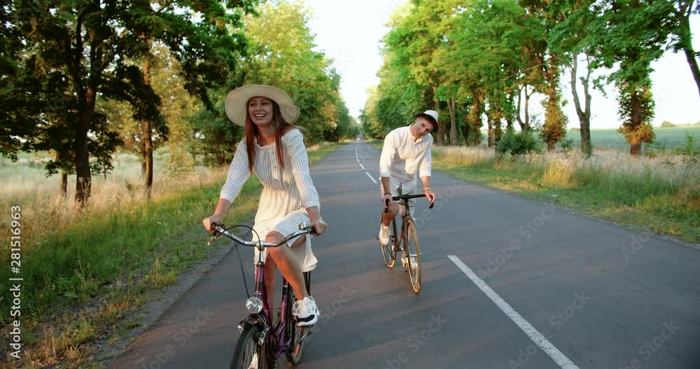 Joyful young couple riding bicycles on countryside road, chatting and enjoying time together, vacations Joyful young couple riding bicycles on countryside road, chatting and enjoying time together, vacations
