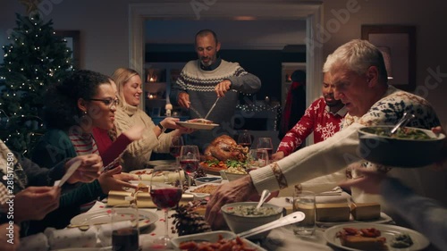 family christmas dinner man cutting turkey serving delicious meal at festive celebration people sitting at table enjoying delicious feast celebrating holiday at home 4k footage photo