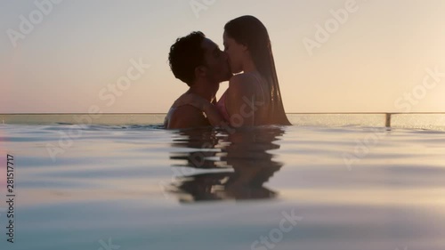 romantic couple kissing in swimming pool enjoying honeymoon vacation at luxury hotel with beautiful view of mediterranean ocean at sunset 4k  photo
