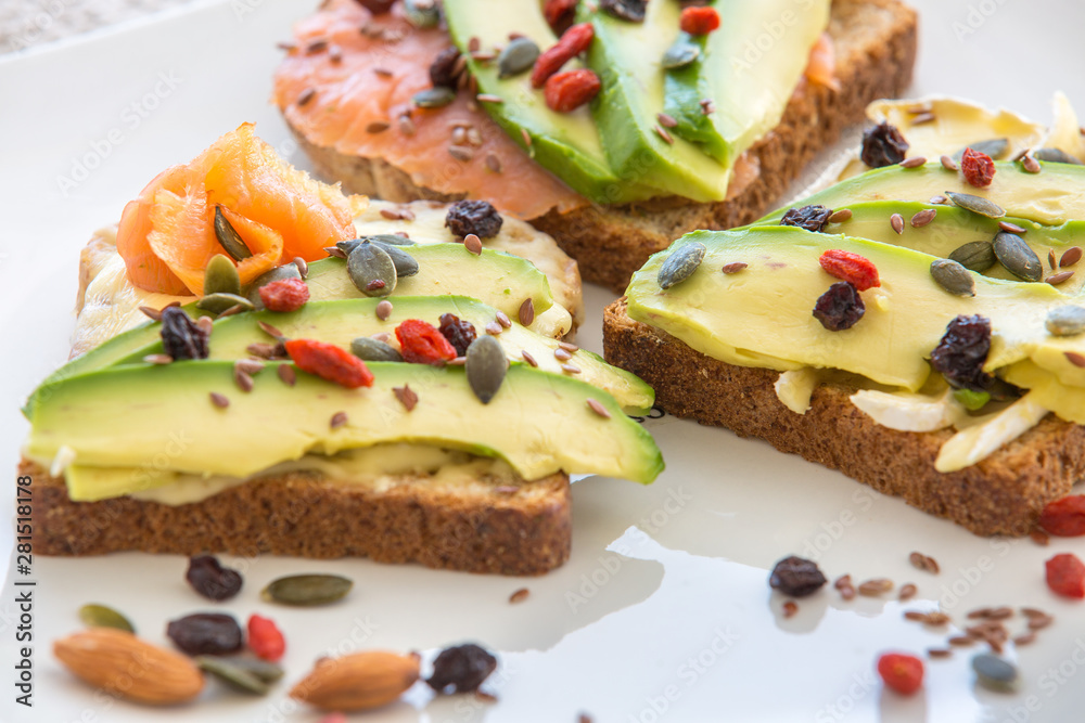 Salmon toast with avocado. Sandwich made with toast with slices of avocado and smoked salmon. Sesame seeds, walnut, linseed, goji berries.Close-up.For healthy concept