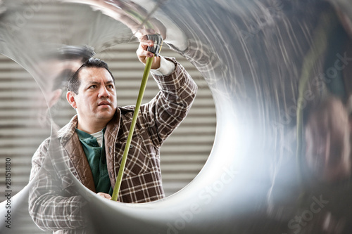 Worker measuring diameter of pipe in factory photo