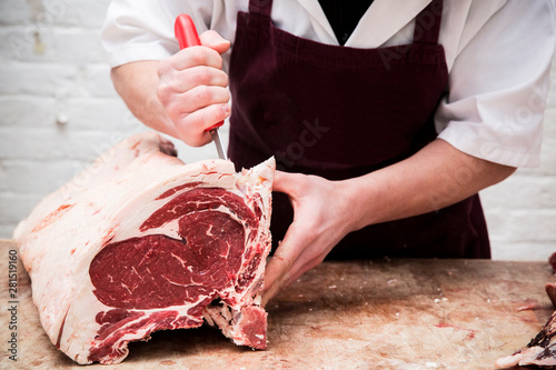 Midsection of butcher chopping beef forerib with knife photo