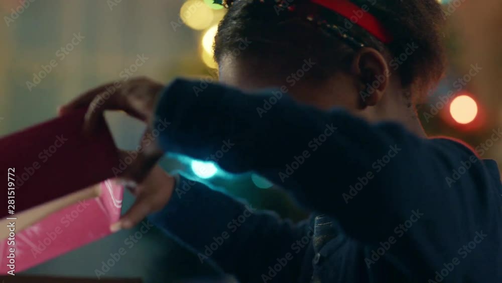 little african american girl unwrapping christmas present looking in box with glow on face surprised child excited for special gift having fun enjoying festive holiday celebration 4k