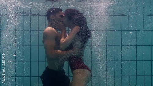 playful couple kissing underwater in swimming pool young people enjoy romantic kiss passionate lovers submerged in water floating with bubbles enjoying romance  photo