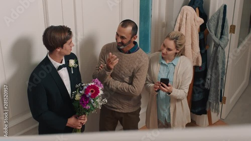 prom night teenage boy looking at beautiful girl walking down stairs wearing glamorous dress for homecoming dance family smiling proud mother and father excited for daughter 4k