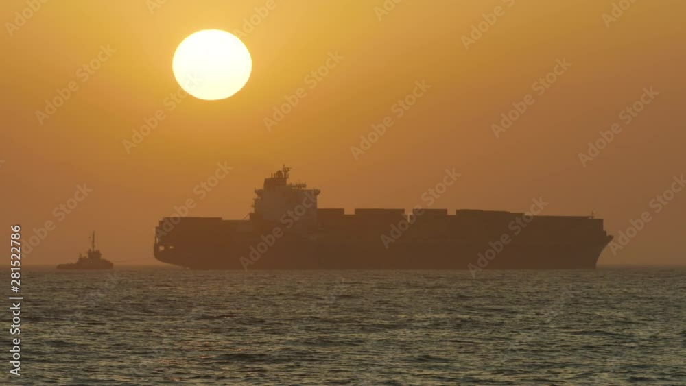 Stunning long shot of a large shipping container moving across the ocean as the sun sets Stunning long shot of a large shipping container moving across the ocean as the sun sets