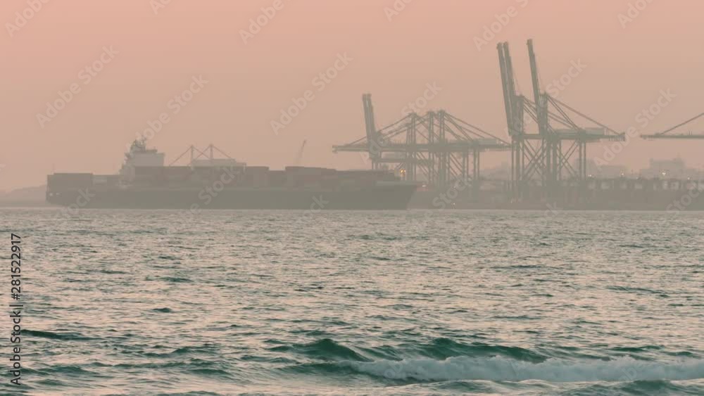 Cargo ship moving towards a shipping port at dusk Cargo ship moving towards a shipping port at dusk