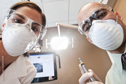 Portrait of dentist with his assistant working on patient in clinic photo