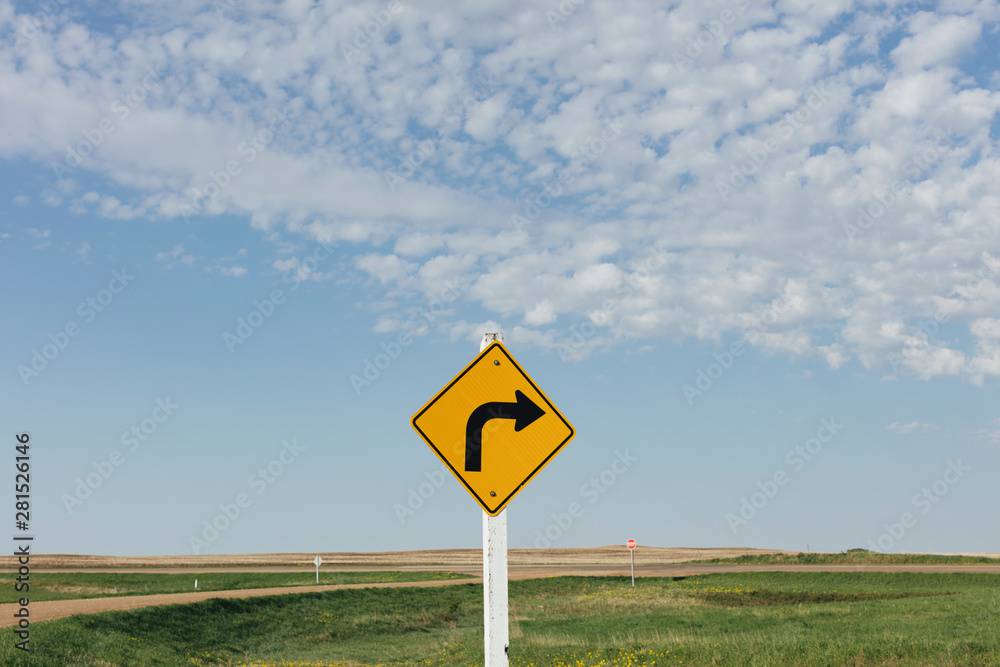 Caution turn ahead sign with rural landscape Caution turn ahead sign with rural landscape