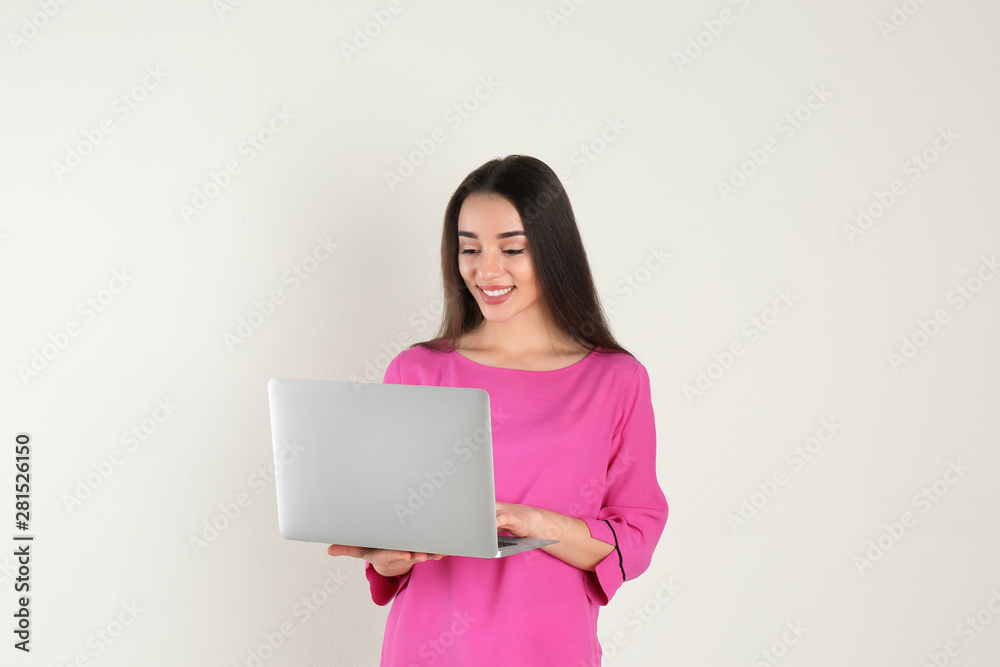 Portrait of young woman in casual outfit with laptop on light background Portrait of young woman in casual outfit with laptop on light background