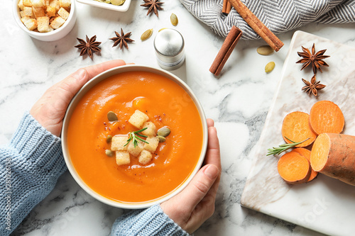 Fotografi Woman with bowl of tasty sweet potato soup at table, top view