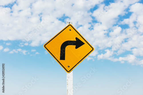 Close up of caution turn ahead sign with cloudy sky