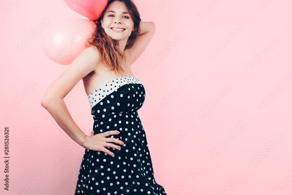Beautiful elegant girl on pink background. Copy space. Party concept. Charming young woman in retro dress with balloons in her hands. Beautiful elegant girl on pink background. Copy space. Party concept. Charming young woman in retro dress with balloons in her hands.