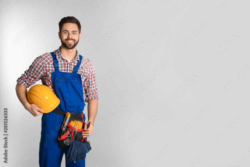 Portrait of construction worker with tool belt on light background. Space for text - obrazy, fototapety, plakaty 