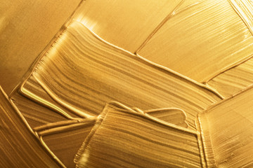 Strokes of gold paint as background, top view