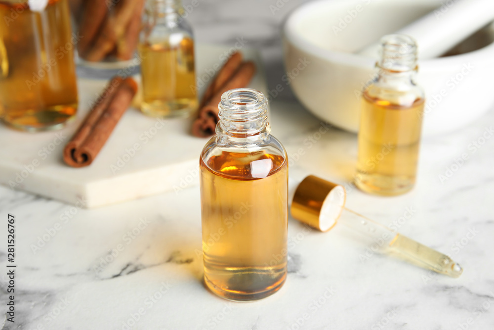 Bottles with cinnamon essential oil on marble table Bottles with cinnamon essential oil on marble table