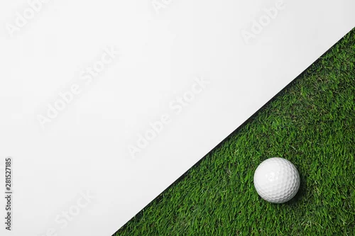 Obraz Piłka golfowa i biały papier na zielonej sztucznej trawie, odgórny widok z przestrzenią dla teksta