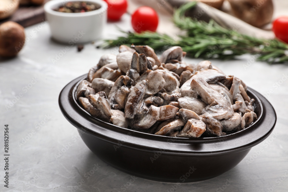 Bowl with delicious cooked mushrooms on grey table Bowl with delicious cooked mushrooms on grey table