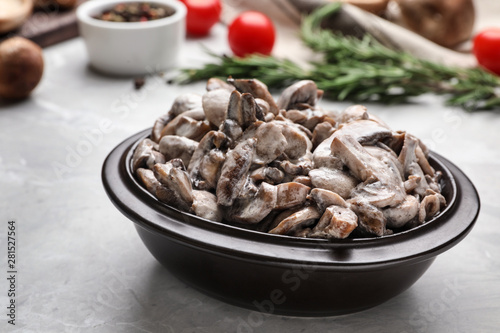 Bowl with delicious cooked mushrooms on grey table