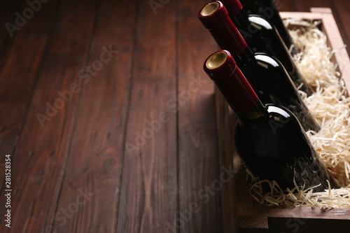 Crate with bottles of wine on wooden table. Space for text