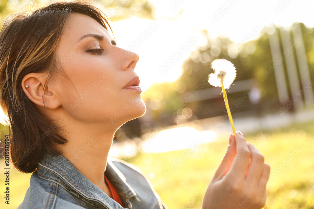 Young woman with dandelion in park on sunny day. Allergy free concept Young woman with dandelion in park on sunny day. Allergy free concept