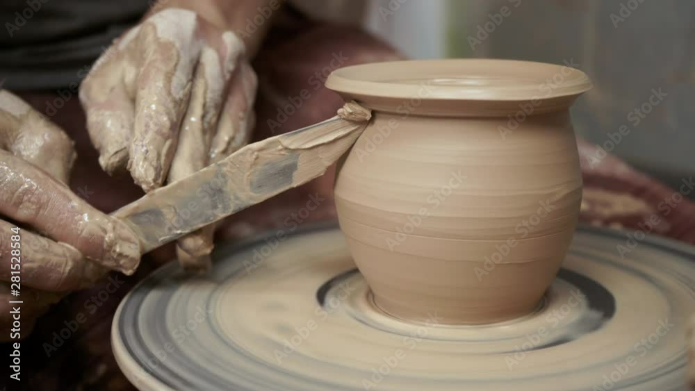 The potter makes a jug of clay. Ceramist. A man makes a vase on a potter's wheel. Hands of the master turn a piece of clay into a jug. Handwork. Pottery. Sculptor's wet hands close up. Clay dishes The potter makes a jug of clay. Ceramist. A man makes a vase on a potter's wheel. Hands of the master turn a piece of clay into a jug. Handwork. Pottery. Sculptor's wet hands close up. Clay dishes