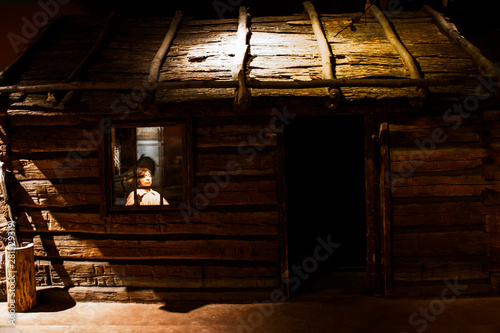 man in the window of an old wooden log home