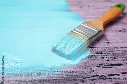 Brush with blue paint on pink wooden background, space for text