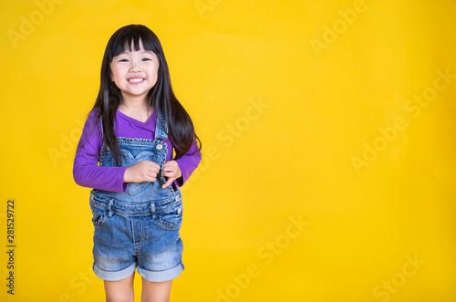 Portrait of young happy little asian girl in uniform isolated on yellow background with copy space. Education for toddler or preschool, childhood lifestyle back to school concept