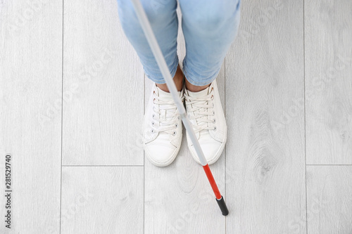 Canvas Print Blind person with long cane standing indoors, top view