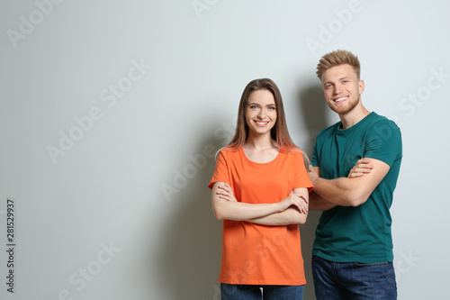 Young couple wearing blank t-shirts on light background. Mockup for design