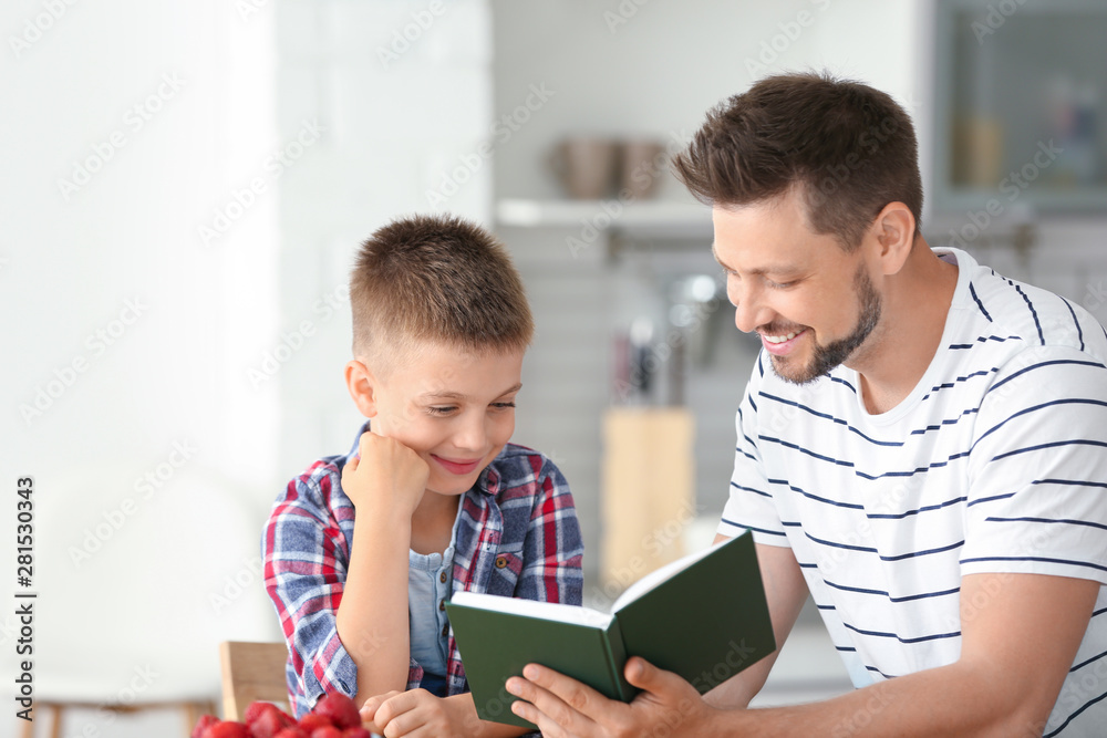 Dad and son reading interesting book in kitchen Dad and son reading interesting book in kitchen