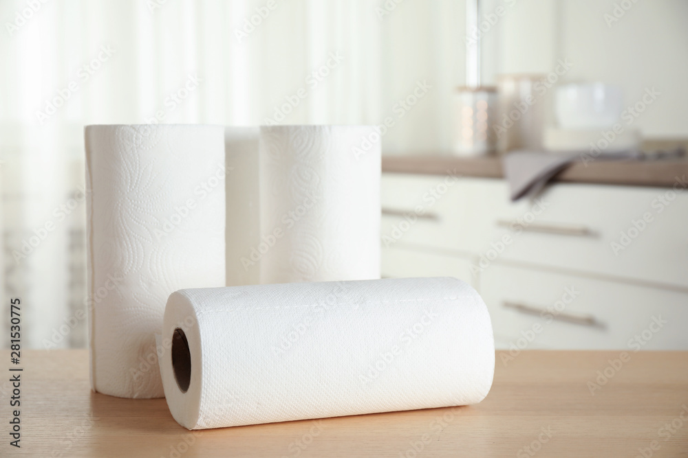 Fototapeta premium Rolls of paper towels on wooden table in kitchen. Space for text