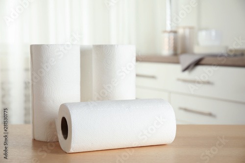 Rolls of paper towels on wooden table in kitchen. Space for text