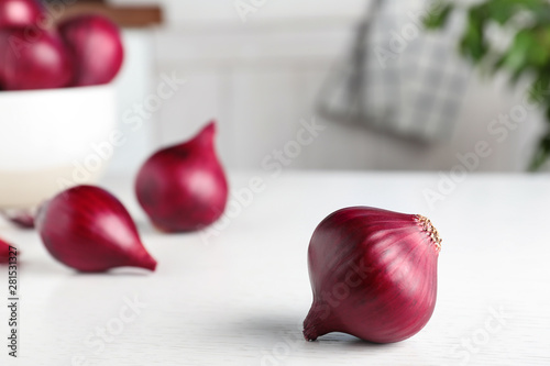 Fresh whole red onion bulb on white wooden table. Space for text
