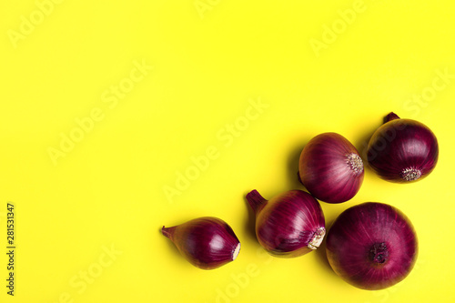 Whole red onion bulbs on yellow background, flat lay. Space for text