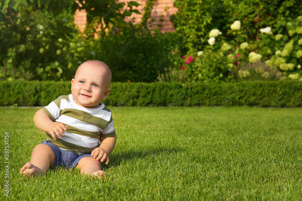 Adorable little baby sitting on green grass outdoors Adorable little baby sitting on green grass outdoors