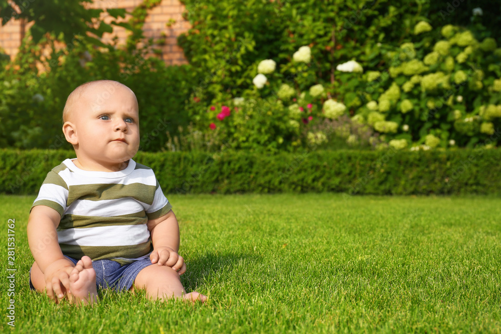 Adorable little baby sitting on green grass outdoors Adorable little baby sitting on green grass outdoors