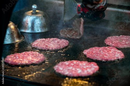 roasting raw marbled beef burger patties on  iron grill  outdoors  photo