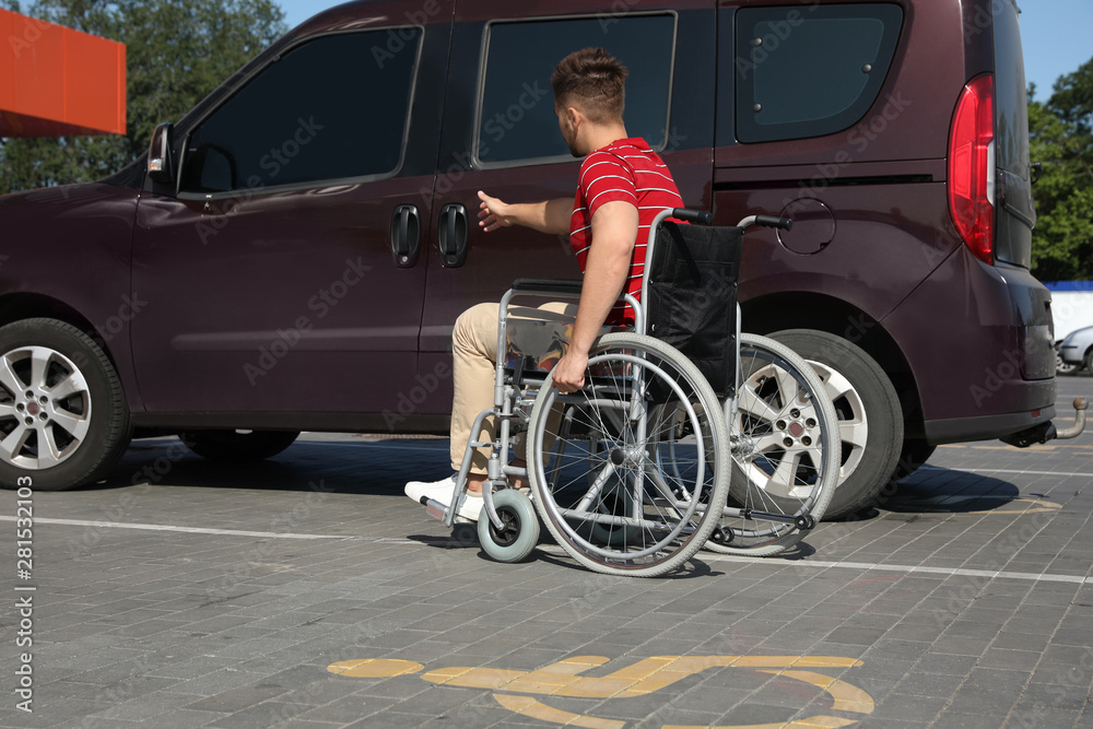 Young man in wheelchair opening door of van on car parking Young man in wheelchair opening door of van on car parking