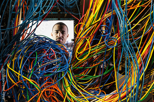 Technician working on tangled mess of cat 5 cables in server room