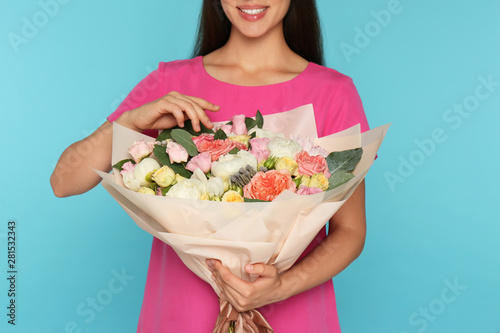 Young woman holding beautiful flower bouquet on light blue background, closeup