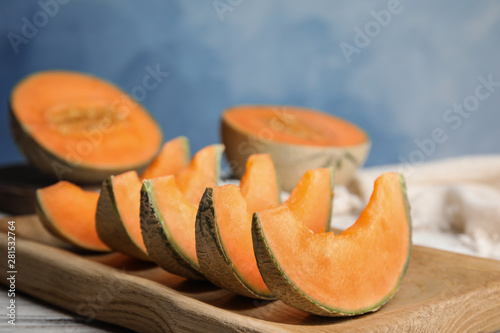 Slices of ripe cantaloupe melon in wooden tray on table