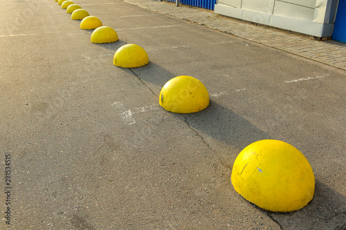 Yellow concrete hemispheres on the parking lot near the retail supermarket so that cars do not park in this place. Artificial obstacle for driving and parking. Anti-parking barrier. © Andrii A
